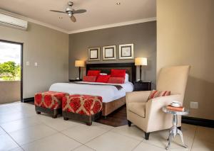 莫科帕内Sofala Lodge的一间卧室配有一张带红色枕头的床和一把椅子
