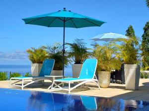 维多利亚Petit Amour Villa, Seychelles的游泳池旁的两把椅子和一把遮阳伞