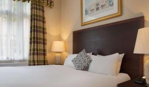 埃文河畔斯特拉特福The Welcombe Golf & Spa Hotel的一间卧室配有带白色床单和枕头的床。