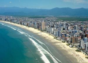 大普拉亚Apto com Piscina e Churrasqueira的享有海滩的空中景色,设有建筑和海洋