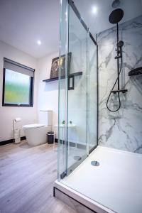 福哈伯斯Opulent, relaxing home with Hot Tub的浴室配有带浴缸的玻璃淋浴间和卫生间。