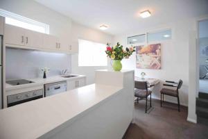 霍巴特Central Hobart - Beautiful Apartment的白色的厨房,在柜台上放花瓶