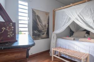 圣皮埃尔La Kazaka Terre Sainte的一间卧室配有一张天蓬床、长凳和钢琴