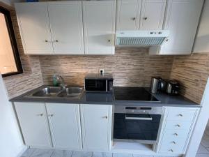 克拉法吉亚Tersanas Beach Apartments的厨房配有白色橱柜、水槽和微波炉