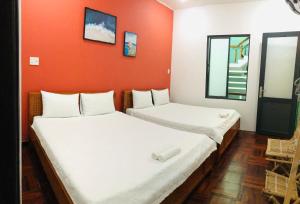 绥和市NẮNG HOMESTAY的橙色墙壁的客房内的两张床