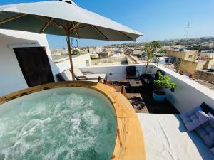 ŻebbuġRooftop Heated Jacuzzi, Fireplace, A Unique Home!的阳台上的热水浴池配有遮阳伞