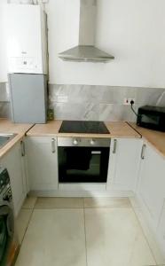利物浦8 Guest Lovely home in Liverpool的厨房配有白色橱柜和黑微波炉