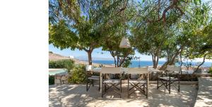 皮索利瓦迪Morfia Villas的海滩上树木下的桌椅