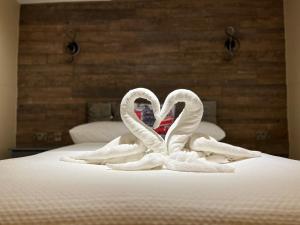 伦敦科莫盖特酒店的两个天鹅,形状像心,坐在床上