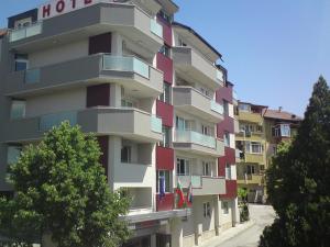 布拉戈耶夫格勒ALPHA family HOTEL的一座高高的公寓楼,设有红色和白色的阳台