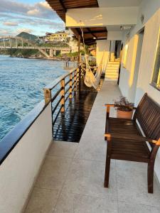里约热内卢Casa Marambaia 2的一张长凳,坐在俯瞰水面的阳台