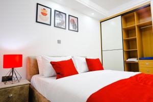 内罗毕Elite Luxury Apartments Kilimani - An Oasis of Serenity and Tranquility的一间卧室配有红色和白色枕头的床