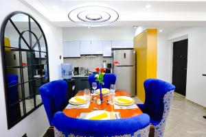 内罗毕Elite Luxury Apartments Kilimani - An Oasis of Serenity and Tranquility的一张带蓝色椅子的餐桌和一间厨房