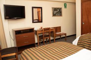 万卡约Hotel Presidente Huancayo - Asociado Casa Andina的配有书桌、桌子和床的酒店客房