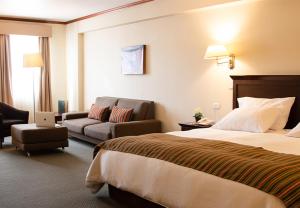 万卡约Hotel Presidente Huancayo - Asociado Casa Andina的酒店客房,配有床和沙发