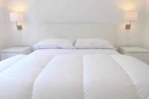 拉帕洛马Luces de la Paloma的一张白色的床,配有白色床单和2个床头柜