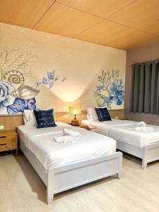 皮皮岛Phi Phi Indigo Hotel的墙上挂着蓝色花卉的房间里设有两张床