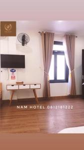 Bản CoKhach san Nam Hotel的客房设有书桌和带窗帘的窗户。