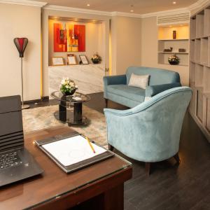 多哈Corp Executive Hotel Doha Suites的办公室,配有一张桌子、一台笔记本电脑和一把椅子