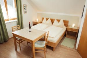 毛特恩Weingut Jakob`s Ruhezeit的一间卧室配有一张床和一张桌子及一瓶葡萄酒