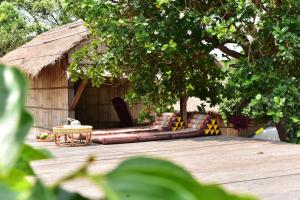 Phumĭ Pu PalLa Villa Hortensia-Mondulkiri的小屋前的木制甲板上的沙发