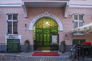 塔林圣奥拉沃酒店的粉红色建筑的前门,有绿色的门