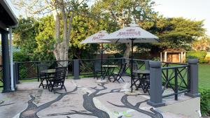 谢普斯敦港Umdlalo Lodge的一个带桌椅和遮阳伞的庭院