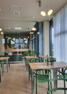 萨图马雷Marida Hotel的餐厅设有木桌和绿色椅子