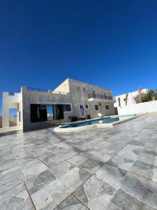 乌姆苏克Magnifique villa avec piscine sur l’île de djerba的一座带瓷砖地板和游泳池的建筑