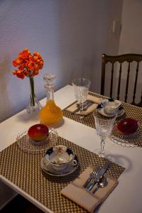 法鲁À dos Reis的一张桌子,上面有盘子和玻璃杯,花瓶上放着橙色的花