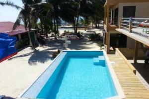 库尔克岛Beach Club Budget Rooms at Popeyes Caye Caulker的一座大型蓝色游泳池,位于房子旁边