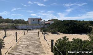 埃斯卡洛Apto Mar de Es Caló, a metros de la playa - Formentera Natural的海滩上的木板路,有建筑