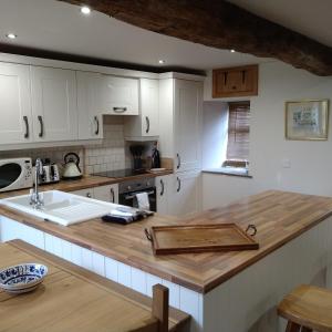 布雷肯Wern Ddu, Defynnog - Brecon Beacons的厨房配有白色橱柜和木制台面