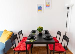 维也纳Pal's Favoriten Apartment的一张带红色靠垫的餐桌和一张黑桌子及椅子