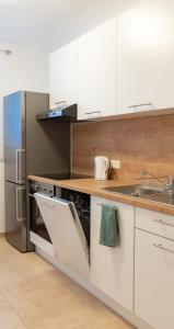 维也纳Pal's Favoriten Apartment的厨房配有白色橱柜和不锈钢冰箱