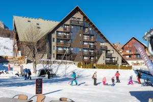 雷阿隆Appartement Chabrières的一群人在建筑物前的雪中滑雪