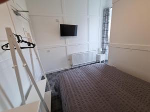 斯特兰拉尔Windsor house的卧室配有一张床,墙上配有电视。