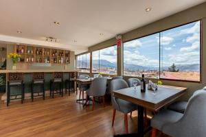 库斯科Tikala Cusco Boutique Hotel的餐厅设有桌椅和大窗户。