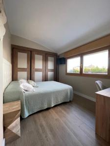 阿斯托加El Roble 9的一间卧室设有一张床和两个窗户。