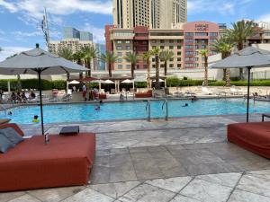 拉斯维加斯Balcony Suite Strip View的一个带两个红色沙发和遮阳伞的游泳池