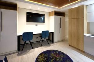 巴科洛德Elegant studio six in Bacolod across Ayala Mall的厨房配有带2把椅子的书桌和电视。