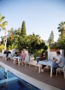 凯麦尔Amsterdam Otel & Suite Apart的一群人坐在游泳池旁的桌子上
