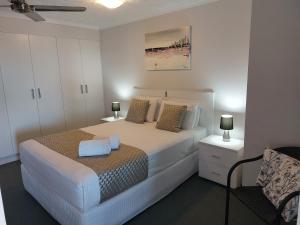 卡伦德拉Sandy Shores Holiday Units的卧室配有白色床、两盏灯和一把椅子