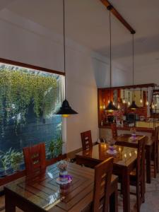 尼甘布多米尼库住宿加早餐旅馆的用餐室设有木桌、椅子和大窗户