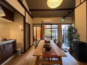 京都至の宿-京都南 Traditional Machiya Guesthouse的厨房以及带木桌和椅子的用餐室。