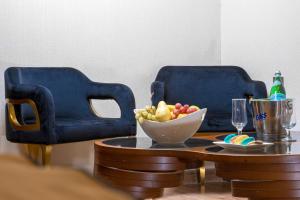 巴格达Al Yarmouk International Hotel的两张蓝色的椅子和一张桌子及一碗水果