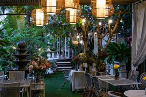 莱卡邦Aranta Suvarnabhumi的餐厅设有桌椅,种植了植物,配有吊灯
