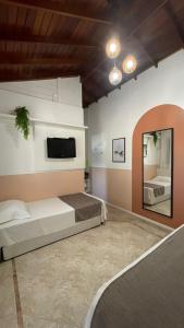 邦比尼亚斯Pousada Casa Mariscal的一间卧室设有两张床,墙上配有电视。