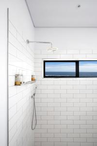 贝蒂湾OnTheRocksBB Solar Powered Guesthouse and Ocean Lodge的白色瓷砖浴室设有窗户和淋浴。
