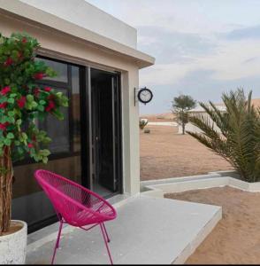 Shāhiq游猎沙漠营地度假酒店的粉红色的椅子,坐在房子外面,有时钟